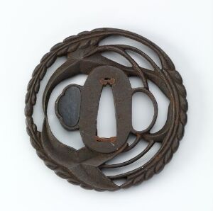  A weathered circular metallic brooch with an intricate looping border and a central horizontal figure-eight design, set against a neutral gray background.