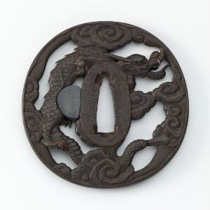  An intricately carved or molded circular bronze disc with a design featuring a stylized dragon surrounded by swirling cloud or wave patterns, set against a light grey background.