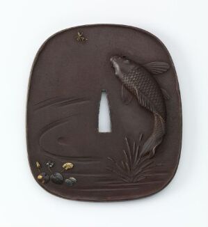  A detailed dark brown netsuke or ornamental carving of a fish surrounded by aquatic plants and hints of gold inlay on a roughly rectangular flattened surface with rounded edges.