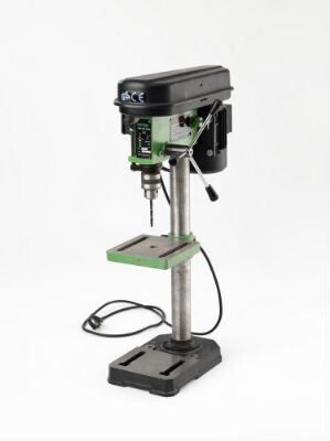  A floor-standing steel drill press from Terje Ekstrøm's workshop, with a black motor housing on top, an adjustable metal table, and a heavy base, set against a white background.