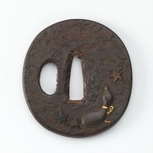  A brown circular Japanese sword hand guard (tsuba) with a pattern of incised stars and an applied design of a rabbit with golden accents on a white background.