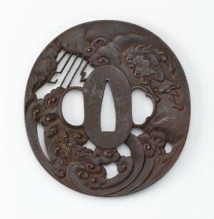  A circular, dark brown, intricately carved openwork disk with a central oval hole and symmetrical design, possibly made of wood, depicting a cultural or historical artifact with no known artist or title.