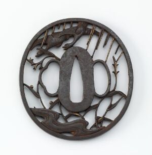  Antique round metal sword guard (tsuba) with a central oval opening and intricate carving, including a cicada motif, set against a light background.