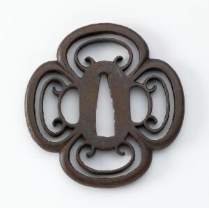  A dark brown, symmetrical, metal ornamental object with a central elliptical cutout surrounded by interconnected rounded lobes, resembling a stylized flower or heraldic emblem, set against a light gray background. Artist's name and title are unknown.