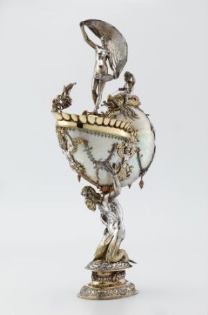  A Nautiluspokal by Mathaeus Wallbaum, showcasing a nautilus shell mounted as a goblet with intricate silver ornamentation and footing, featuring richly detailed decor, in a neutral and metallic color scheme.