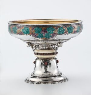  A decorative goblet with a silver tone and an elaborate inlaid band of turquoise and coral colors around the upper part, standing on a detailed footed base.