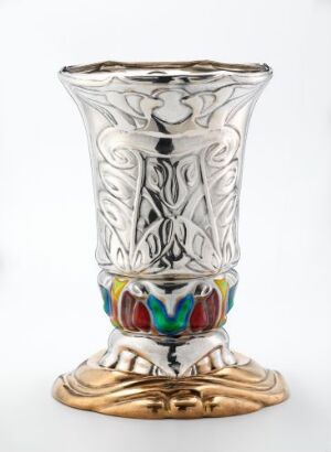  An elaborate vase with a reflective gold base designed to resemble a flower or leaves, a vibrant, multicolored band in jewel tones, and a silver-colored body with embossed Art Nouveau or Art Deco patterns, culminating in an outwardly flaring rim.