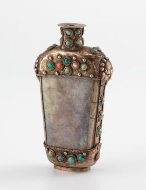  An ornate, aged metallic vessel resembling oxidized copper or bronze, decorated with turquoise and reddish-brown inlaid circular patterns, featuring a crown-like stopper and finial-like protrusions on the bottleneck.