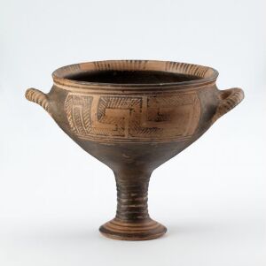  An ancient ceramic vessel with a narrow base and flaring body, adorned with a detailed geometric pattern band and linear grooves, featuring two small side handles. The colors are warm brown with darker accents on the decorations.