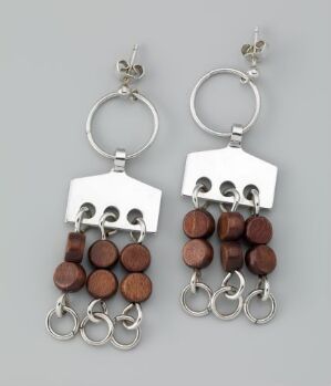  A pair of silver and wood earrings by PLUS, featuring polished silver rings and geometric shapes attached to warm brown, polished wenge beads, creating a harmonious contrast of color and texture.