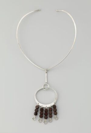  A silver necklace by artist Anna-Greta Eker featuring a simple neck wire with a circular silver pendant from which multiple polished wenge wood charms are suspended in a symmetrical pattern against a light gray background.