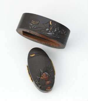  Two traditional Japanese lacquered objects on a white background. The top piece is an oval lid decorated with gold inlay of natural motifs, while the bottom piece is a slightly curved oval box featuring scenes of Japanese iconography highlighted with gold. Both pieces exhibit meticulous craftsmanship and subdued, rich colors against the lustrous dark material. Artist name and title are unknown.