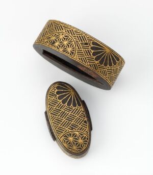  Two oval-shaped trinket boxes with dark backgrounds and gold geometric and sun-like patterns on a bright white surface.