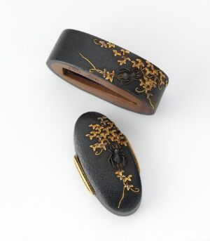  Two oval-shaped black lacquered objects with intricate gold floral designs, resembling a traditional Japanese inro, lying against a light background. Artist name and title are unknown.