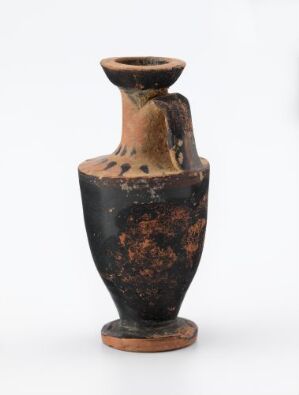  An ancient ceramic vessel with a rounded base and a narrow neck, featuring a deep brown and black coloring with orange-brown patches, photographed against a plain background. Artist name and title remain unknown.