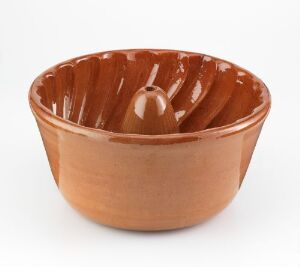  A terracotta ceramic bowl with a fluted interior and a built-in citrus juicer at the center, placed against a light gray background.