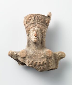  A beige-colored ceramic figurine titled "Chtonic goddess" by an unknown artist, depicting a stylized female deity with circular eyes and a flared crown on a plain white background. The object has a primitive, weathered look suggestive of cultural significance in ancient times.