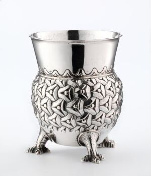  A decorative silver chalice with embossed Celtic or Norse knotwork design in the middle section and three clawed feet, set against a plain white background. Artist name and title are unknown.