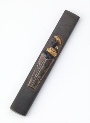  A dark rectangular bookmark or ceremonial item with a golden eagle emblem at the top and a sword or cross design in relief, against a light background. The bookmark is positioned diagonally, with the objects' colors including matte black, golden yellow, brown, and silvery-gray. Artist name and title are unknown.