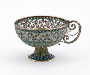  Ornate, footed bowl with intricate openwork design and enameled colors of white, red, blue, and green on a pedestal base with a decorative handle, set against a neutral background.