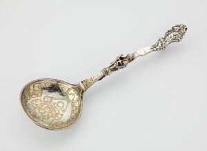  An ornate, antique silver spoon with gilded bowl and detailed handle, showcasing intricate engravings and high craftsmanship from an unidentified artist.