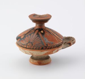  An ancient, painted clay decorative object known as "Kantarosgruppen." It features a shallow, wide-rimmed bowl on a pedestal with large, curved handles, and is adorned with a geometric, radial pattern in earthy brown and orange tones. Artist remains unidentified.