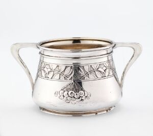  A small, silver sugar bowl designed by Gustav Gaudernack, featuring intricate geometric and grape cluster decorations etched into the upper band, with curved handles and a polished finish.