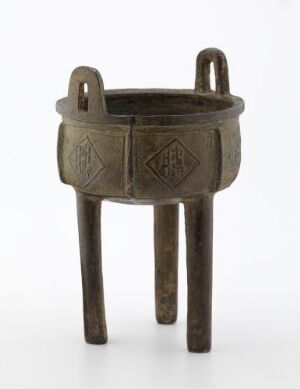  An ancient bronze tripod vessel with a round basin, decorated with geometric patterns, supported by three straight legs, and two loop handles, against a white background.