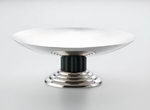  An elegant Tazza by Jean-Emile Puiforcat, featuring a shiny metallic bowl on a dark ribbed bakelite column and a tiered metallic base.