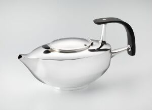  A modern silver teapot with ebony handles, designed by Leif Stangebye-Nielsen for "Diplomoppgave SHKS," showcasing a polished finish and sleek silhouette on a light gray background.