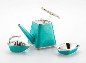  A vibrant turquoise tea set with a geometric shaped tea pot, sugar bowl, and creamer, featuring chrome-colored handles and hinges against a white background. Artist and title unknown.