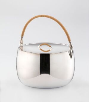  A polished sterling silver satchel or tea caddy designed by Magnus Stephensen, with a reflective surface creating highlights and shadows. The piece has a rounded form and includes a tan braided or woven handle attached by silver fittings and a simple circular clasp on top.