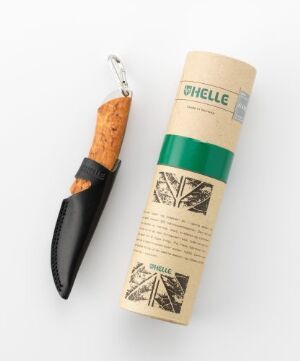  A stainless steel and wood (possibly cork) handled knife with a black leather sheath next to its cylindrical cardboard packaging featuring a green label with the brand 'HELLE', and illustrations of trees and a tent, suggestive of outdoor use.