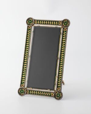  An antique-style vertical picture frame with ornate gold beading and green and red rosette corner accents against a light background, reflecting craftsmanship suggestive of a Victorian aesthetic.