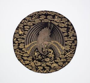  A circular emblem-like artwork featuring a stylized bird of prey with outstretched wings in gold against a black background filled with interlocking golden cloud-like motifs.