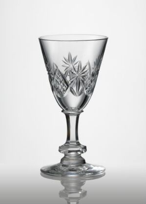  A transparent glass goblet with a bell-shaped bowl featuring skjærslipt and fasettslipt floral design decorations on a plain grey background. Artist name unknown.