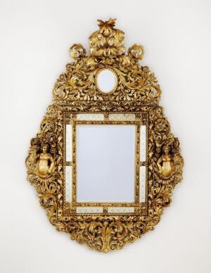  An ornate golden framed mirror, "Speil" by an unidentified artist, with relief and figure-carved foliage patterns in the wood and oil gilded with metal leaf. The mirror glass features etched floral decorations, set against a white background.