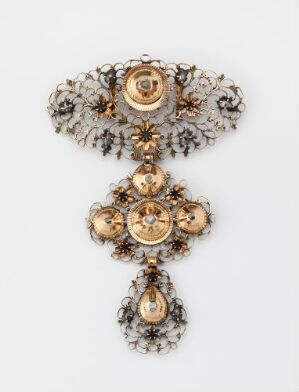  An intricate gold and filigree cross-shaped "Brystsmykke" (breast jewelry) with a horizontal filigree bar at the top and a central dangle cross, each with floral patterns and likely inset stones, made by an unknown artist.