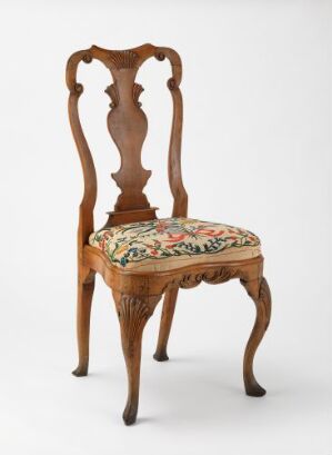  A traditional wooden chair with a polished brown finish and an ornate, open-designed backrest with curvilinear shapes. It features a colorful tapestry cushioned seat with floral patterns in reds, greens, yellows, and blues, and gracefully curving cabriole front legs.