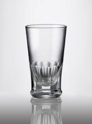  A clear faceted drinking glass on a reflective surface, demonstrating the intricate designs cut into the lower part with a smooth upper segment, made from blown glass with no discernible color, crafted by an unknown artist.