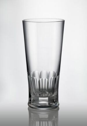  A clear, empty glass with a faceted decoration at the base, exhibited against a gradient gray background, illustrating the craftsmanship of blown glass with faceted cut decor by an unknown artist.