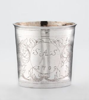  A cylindrical silver cup known as "Beger" crafted by Anders Olsen Pharo, featuring engraved acanthus leaves surrounding a shield-shaped cartouche with the initials "S.A.S." above the year "1709" on its outer surface.