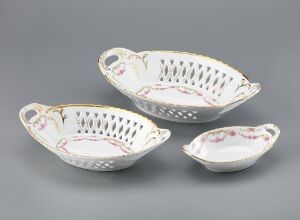  A set of three elegant white porcelain serving dishes with cut-out design edges, detailed floral print inside, and gold trim on the handles and rims.