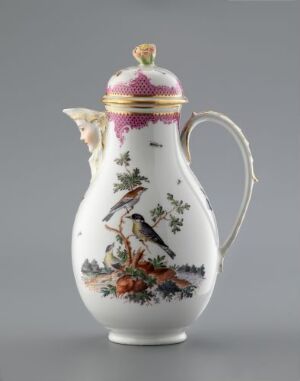  An intricately decorated porcelain jug with a white background, featuring colorful birds and foliage, a gold and magenta band near the top, and a domed lid with a magenta and gold finial.