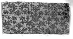  A black and white photo of an ornate floral-patterned fabric, with intricate flowers and leaves spread across the material in varying shades of gray.