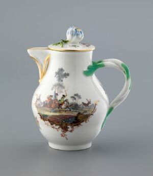  An antique white porcelain jug with a pastoral scene painted in earth tones and surrounded by a gold trim, a green handle resembling a twig with leaves, and a blue floral finial on the lid.