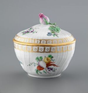  A Royal Copenhagen porcelain bowl with a lid, featuring hand-painted floral designs, Greek key patterns with gold accents, and a small bird figurine on the top.