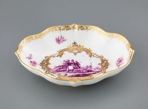  Ornate scalloped-edge porcelain dish with gold trim and central purple landscape cartouche surrounded by floral motifs against a grey background. Artist name and title unknown.