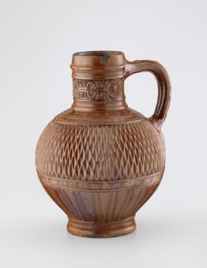  A light brown ceramic jug with a textured design and a single handle, displayed against a light grey background.