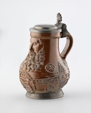  A traditional reddish-brown stoneware beer stein with a pewter lid, showcasing ornamental embossed designs and a sturdy handle.